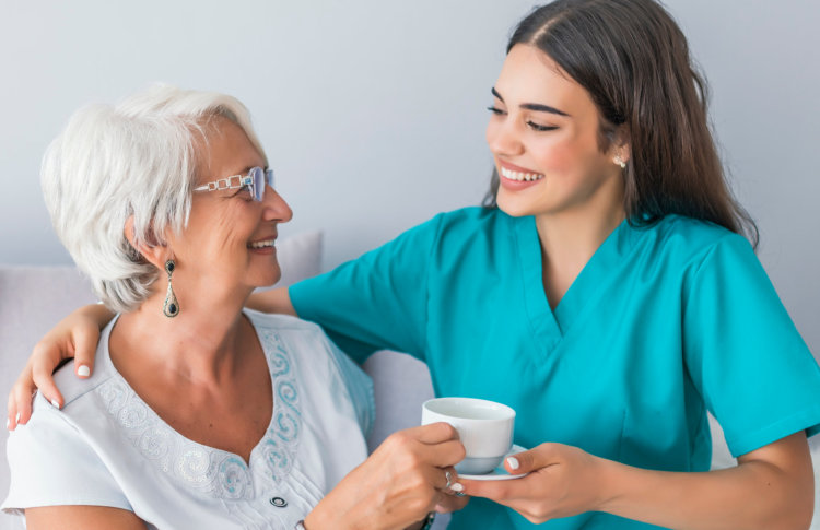 aide serving tea to senior woman